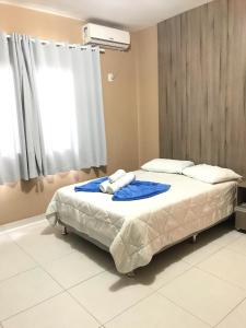 Schlafzimmer mit einem Bett mit blauer Bettwäsche und einem Fenster in der Unterkunft Conquista Palace Hotel in Vitória da Conquista