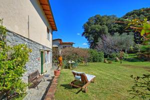 einen Garten mit einem Tisch und Stühlen sowie einem Gebäude in der Unterkunft Casa al Bosco by PosarelliVillas in Ameglia
