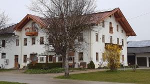 ein weißes Haus mit einem Baum davor in der Unterkunft Pension Baumgartner in Rott am Inn