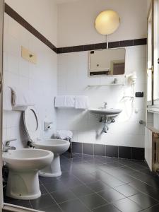 bagno con 2 servizi igienici, lavandino e specchio di Hotel Boston a Milano