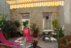un patio al aire libre con mesa, sillas y plantas en La Maison Bleue de Sigean, en Sigean