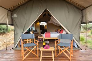 a tent with chairs and a bed in it at Tlouwana Camp in Kasane