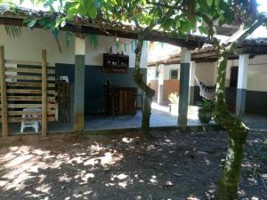 a house with a tree in front of it at Sitio Santo Antonio HOSTEL in Ilhéus