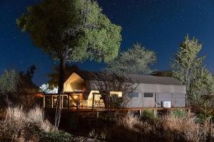 a large white trailer parked under a tree at night at Tlouwana Camp in Kasane