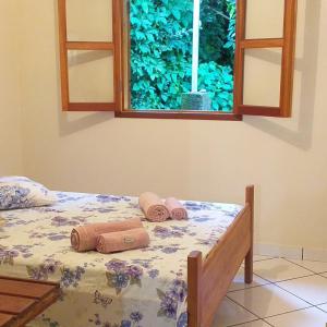 a bed with towels on it with a window at Pousada Murmúrio das Águas in São Francisco Xavier