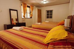 a hotel room with two beds with yellow and orange sheets at Quinta Adela Bed & Breakfast in San Pedro de Atacama