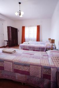 two beds in a bedroom with orange curtains at Quinta Adela Bed & Breakfast in San Pedro de Atacama