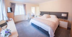 a bedroom with a bed and a desk with a lamp at Riseden Bed and Breakfast in Maidstone