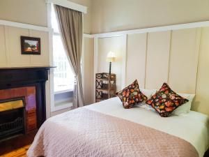 1 dormitorio con cama con almohadas y chimenea en Bauhenia Guesthouse, en Potchefstroom