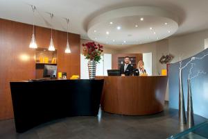 a man in a suit sitting at a reception desk at Metropolis - Hotel di Charme in Rome