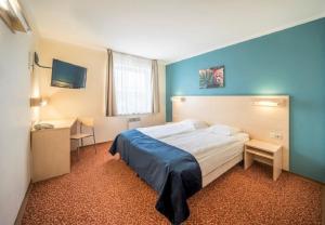 a bedroom with a bed and a desk and a television at Rija Bauska Hotel in Bauska