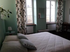 um quarto com uma cama branca com almofadas e janelas em AMBIANCES chambres d 'hôtes em Baye