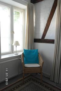 a chair with a blue pillow sitting next to a window at Gästehaus am Krähenteich in Lübeck