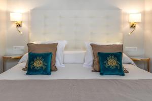a white bed with two blue pillows on it at Hostal Boutique Plaza Cantarero in Nerja