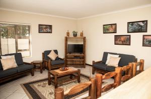 a living room with couches and a tv at Rothesay House in Bloubergstrand