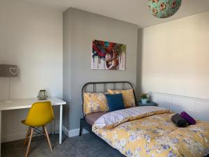 a bedroom with a bed and a yellow chair at Buccleuch Apartment in Kettering
