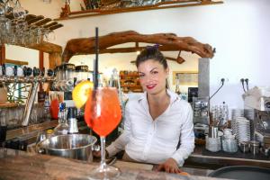 une femme debout derrière un bar avec un verre dans l'établissement Piccolo Ranch, à Pula