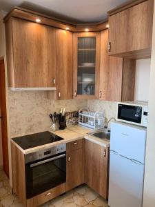 a kitchen with wooden cabinets and a white refrigerator at Vegas Zugló in Budapest