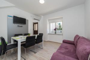 a living room with a purple couch and a table at Balen city central house for 8 in Novalja