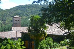 a building with a tower and a mountain in the background at Le couvent côté jardin in Rocles