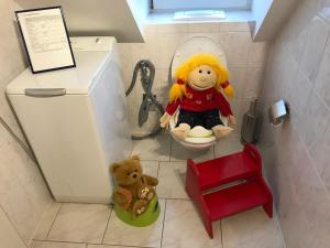 eine Spielzeugpuppe, die auf einer Toilette mit einem Teddybär sitzt in der Unterkunft Leipziger Logis in Leipzig