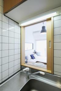 a bathroom with a mirror above a sink and a bed at Fukuromachi#702 in Hiroshima