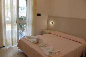 biała sypialnia z łóżkiem i ręcznikami w obiekcie Hotel Al Bosco w mieście Ischia