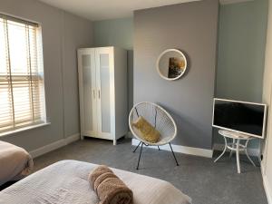 Schlafzimmer mit einem Bett, einem TV und einem Stuhl in der Unterkunft Buccleuch Apartment in Kettering