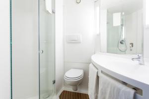 Baño blanco con aseo y lavamanos en Ibis Valencia Alfafar en Alfafar