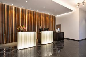 a man standing at a desk in a lobby at H+ Hotel Bremen in Bremen