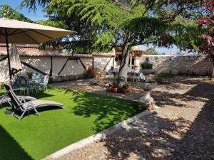 a yard with a green lawn with a tree and chairs at Casa Rural Pedraza in Pedraza-Segovia