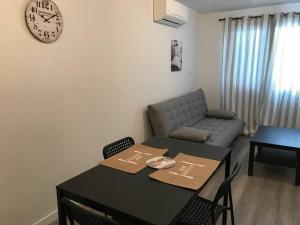 a living room with a table and a couch and a clock at Corté Centre Corse in Corte