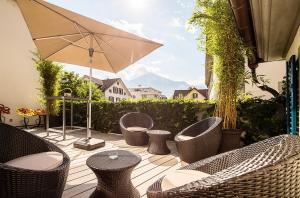 eine Terrasse mit Stühlen, Tischen und einem Sonnenschirm in der Unterkunft Hotel Engel in Stans