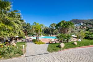 a resort with a swimming pool and palm trees at Cefalù In Casa in Cefalù