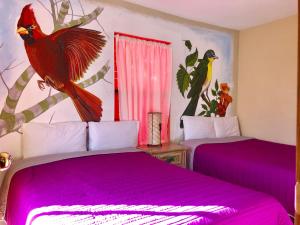 a bedroom with two beds with purple sheets and a bird on the wall at Hotel JADE in Mesa Colorada