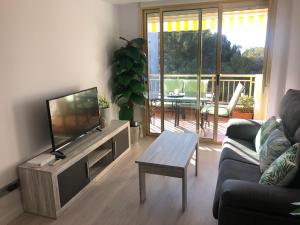 uma sala de estar com uma televisão, um sofá e uma mesa em La Moderna Apartament em Salou