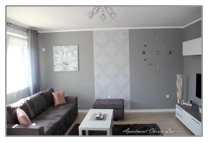 uma sala de estar com um sofá e um relógio na parede em Apartment Cherry Lux em Zrenjanin