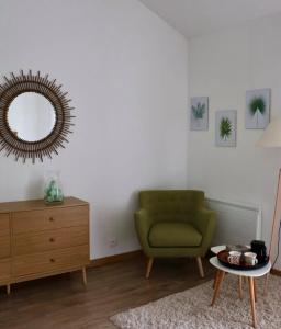 a living room with a green chair and a mirror at Le Chai de Villiers in Villiers