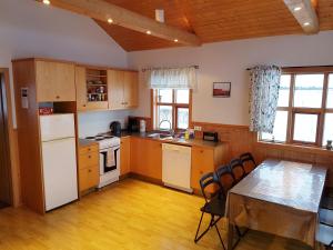 a kitchen with a white refrigerator and a table with chairs at Vorsabær 2 Holiday Home in Fjall