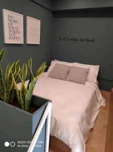 una camera da letto con un letto con lenzuola bianche e una pianta di Urban loft II a Salonicco