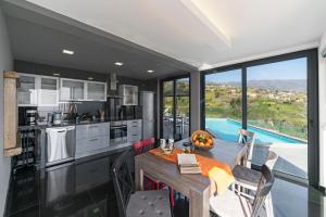 una cucina con tavolo da pranzo e una grande finestra di Villa Clementina | Cliffs&Ocean | Heated Pool a Prazeres