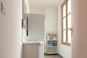 a white bathroom with a sink and a mirror at Appartement Duplex Totalement Meublé et Équipé in Lignières