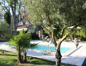 a swimming pool with two trees in a yard at Le Chai de Villiers in Villiers
