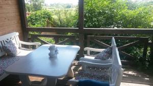 une table et des chaises sur une terrasse avec une fenêtre dans l'établissement Domek na Wzgórzu, à Ryn