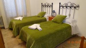 ポソ・アルコンにあるAlojamientos Guiradoのグリーンベッド2台(タオル付)が備わる客室です。