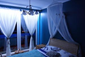 a bedroom with blue walls and white curtains and a bed at Morski Apartament in Ustka