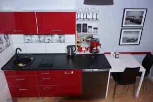 a small kitchen with red cabinets and a sink at Morski Apartament in Ustka