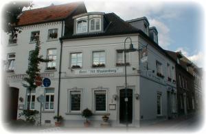 ein großes weißes Gebäude mit einem Schild darauf in der Unterkunft Hotel Alt Wassenberg in Wassenberg