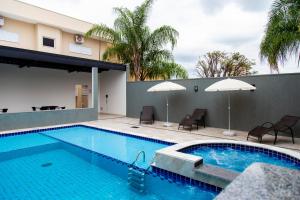 a swimming pool with chairs and umbrellas next to a building at Revitalle Hotel in Votuporanga