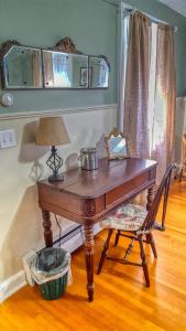 einen Tisch mit einer Lampe und einem Stuhl in einem Zimmer in der Unterkunft Lilac Inn in Brandon